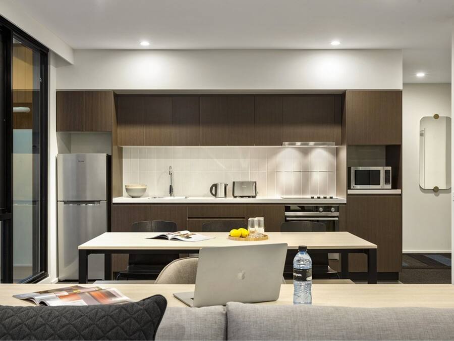 Cocina moderna con comedor, que incluye un refrigerador, microondas y una mesa con una computadora portátil y una botella de agua.