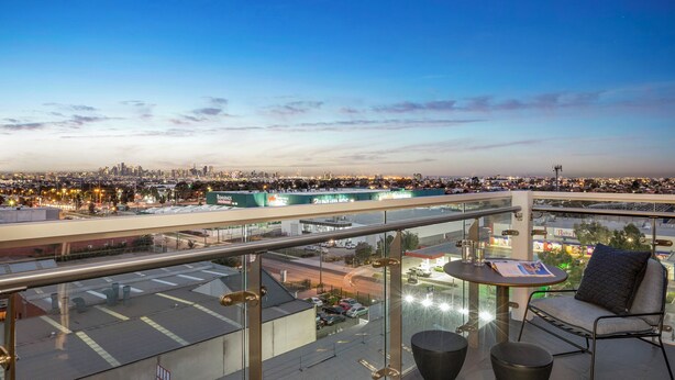 A balcony with a glass railing overlooking a cityscape at dusk. - Quest Maribyrnong (Maribyrnong)