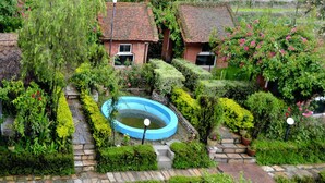 Ein Garten mit Swimmingpool, Steinpfaden und zwei Häusern mit Ziegeln und Tonziegeldächern.