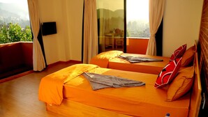 Ein Hotelzimmer mit zwei Betten, Holzboden, einem Wandfernseher und Blick ins Freie.