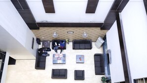 A modern lobby with black sofas arranged in a semi-circle, a coffee machine, and a small table with newspapers. - Hotel Paradise Inn (New Delhi)
