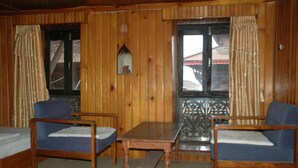 A wooden room with two blue chairs, a wooden table, and a bed. - Unique Guest House (Bhaktapur)