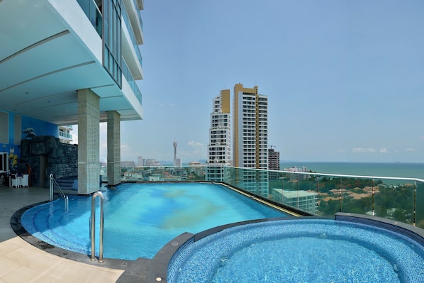 A rooftop infinity pool with a clear view of the ocean and city skyline.