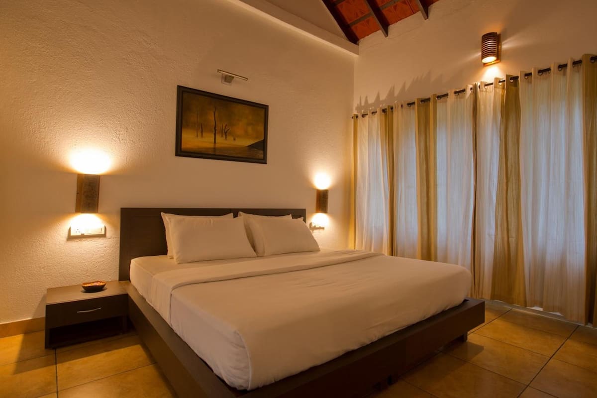 A neatly made bed in a room with a wooden headboard, two bedside tables with lamps, and a painting on the wall.