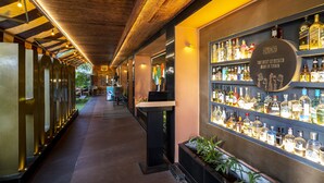 A bar area with a wooden ceiling, a counter, and shelves stocked with various liquor bottles. - Infiniti Hotel & Spa (Indore)