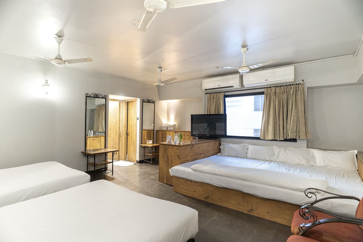 Una habitación de hotel con dos camas individuales, un escritorio de madera, un televisor y un ventilador de techo.