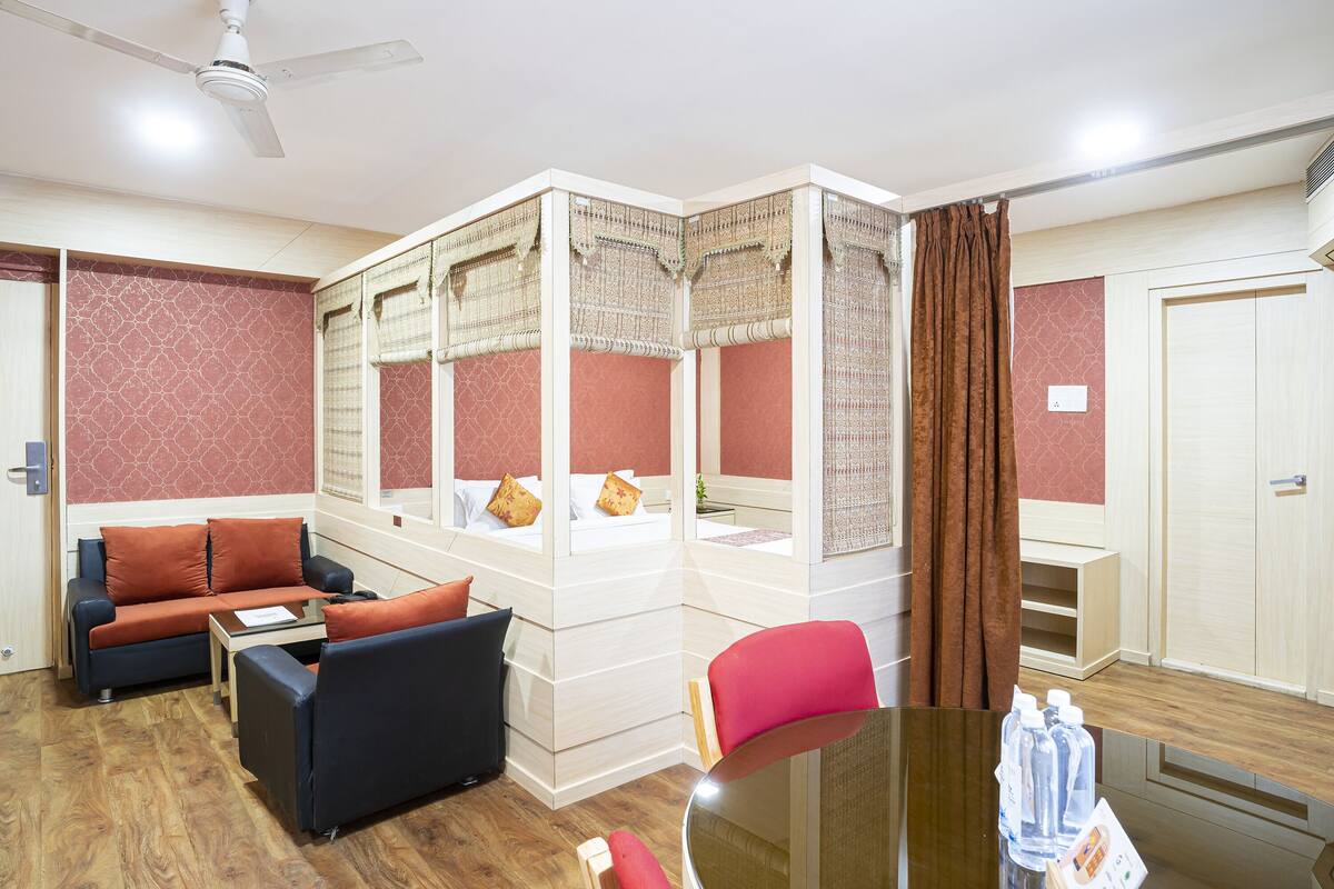 Habitación de hotel con cama, sofá, una mesita y una mesa de vidrio con botellas de agua.