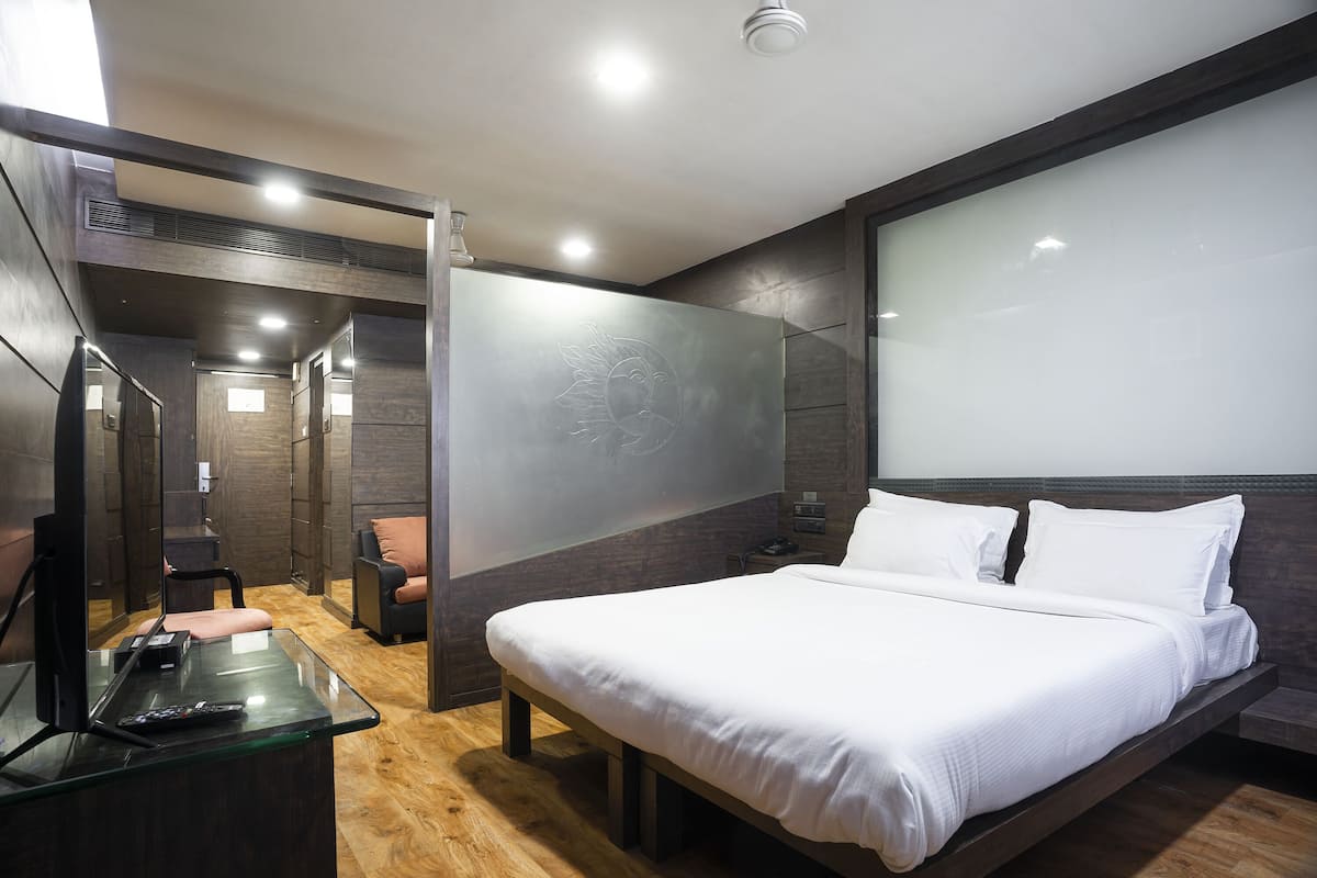 Un dormitorio moderno con una cama grande, un escritorio de vidrio y una zona de estar.