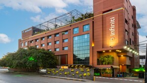 A modern hotel with a prominent Infinity sign, multiple floors, and a rooftop garden. - Infiniti Hotel & Spa (Indore)