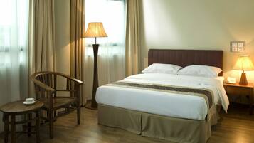 Une chambre d’hôtel avec un lit, une chaise, une table et une lampe.