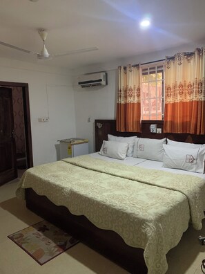 A bedroom with a bed, an air conditioner, a window with curtains, and a ceiling fan. - HighLander Guest House (Aburi)