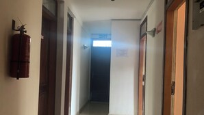 A corridor with doors on both sides, a fire extinguisher on the left, and a sign on the right wall. - HighLander Guest House (Aburi)