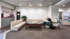 A reception area with a sofa, a coffee table, a lamp, a microwave, and a refrigerator. - Sawa Hotel (Fujikawaguchiko)