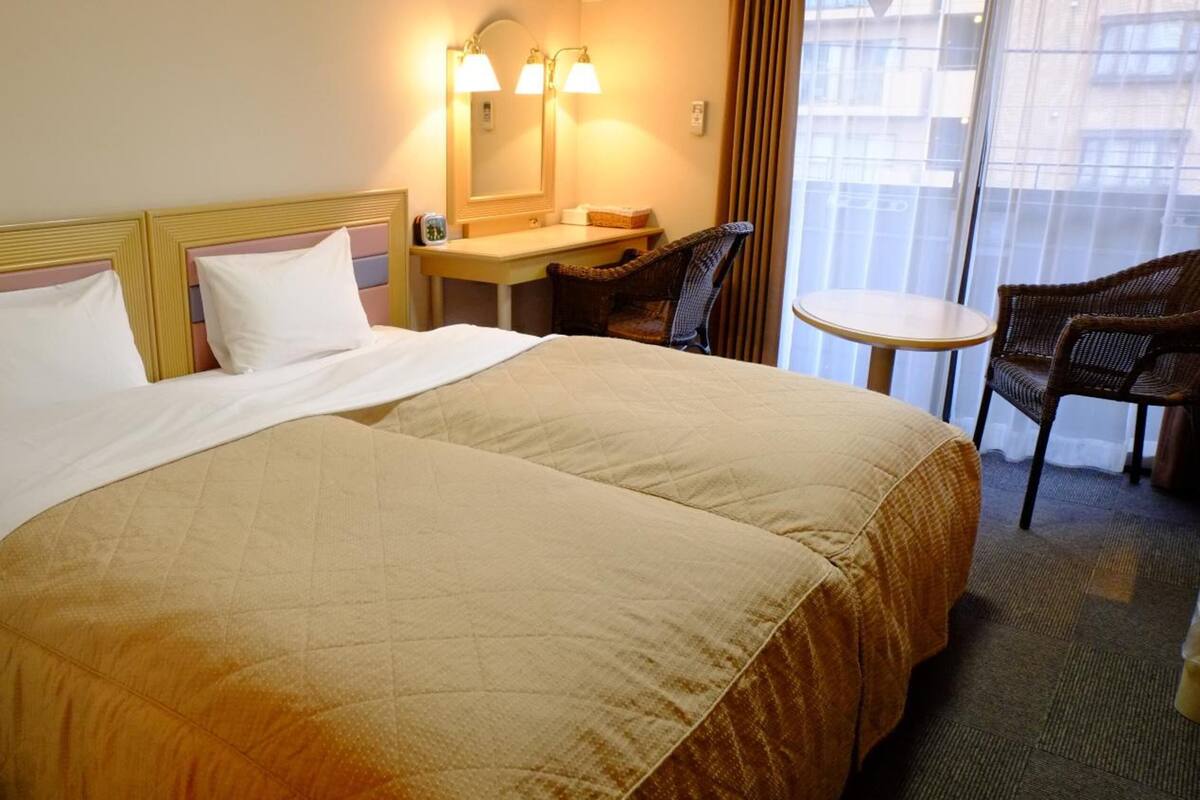 A hotel room with a large bed, a desk, a chair, and a small table.