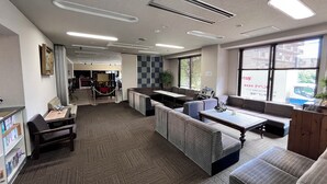 A hotel lobby with seating areas, a reception desk, and a view of the outside through large windows. - Sawa Hotel (Fujikawaguchiko)