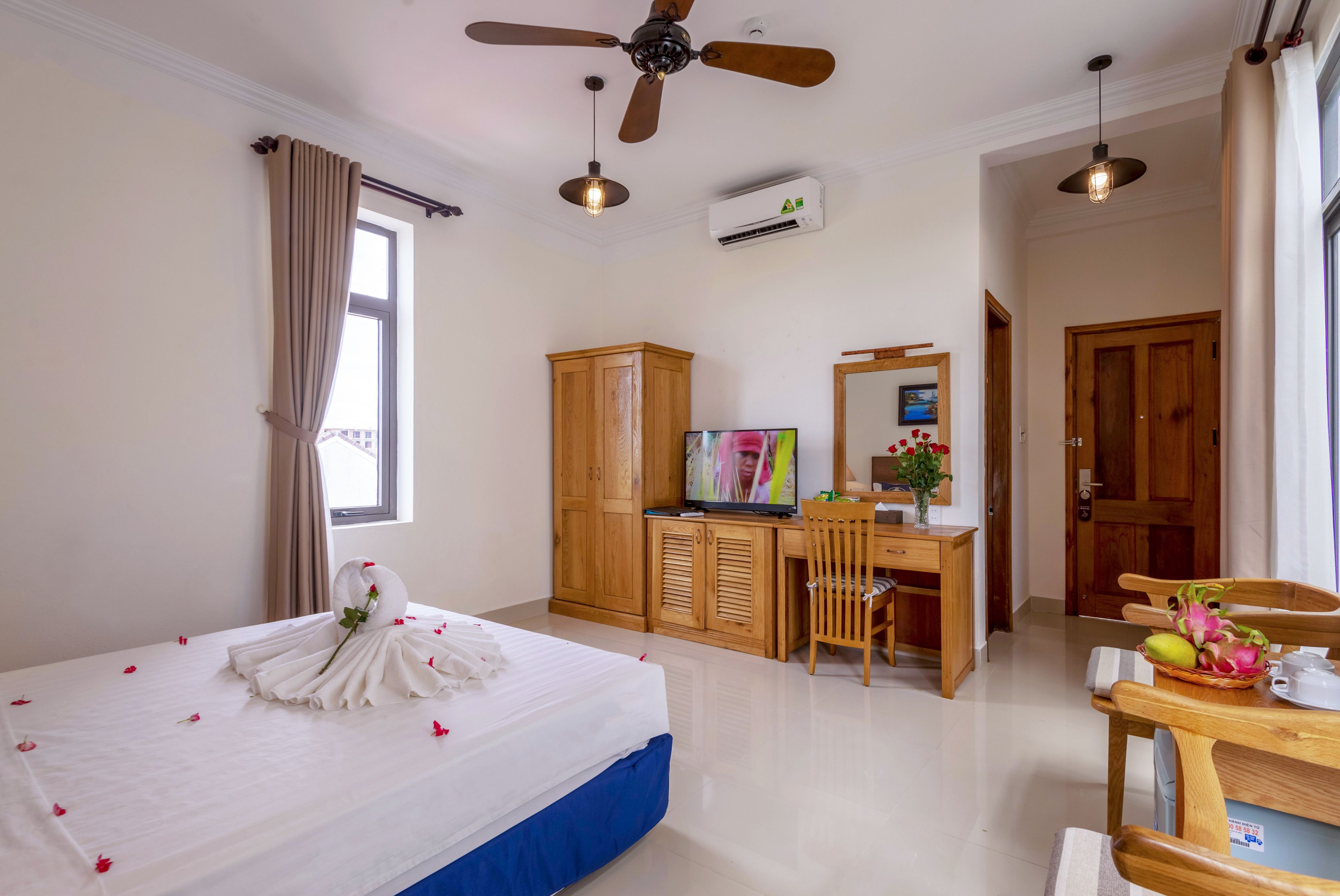 A hotel room with a bed, a desk, a television, and a dining area.