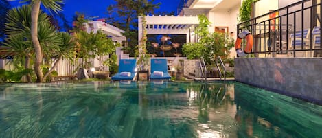 Una piscina al aire libre, sillones reclinables de piscina