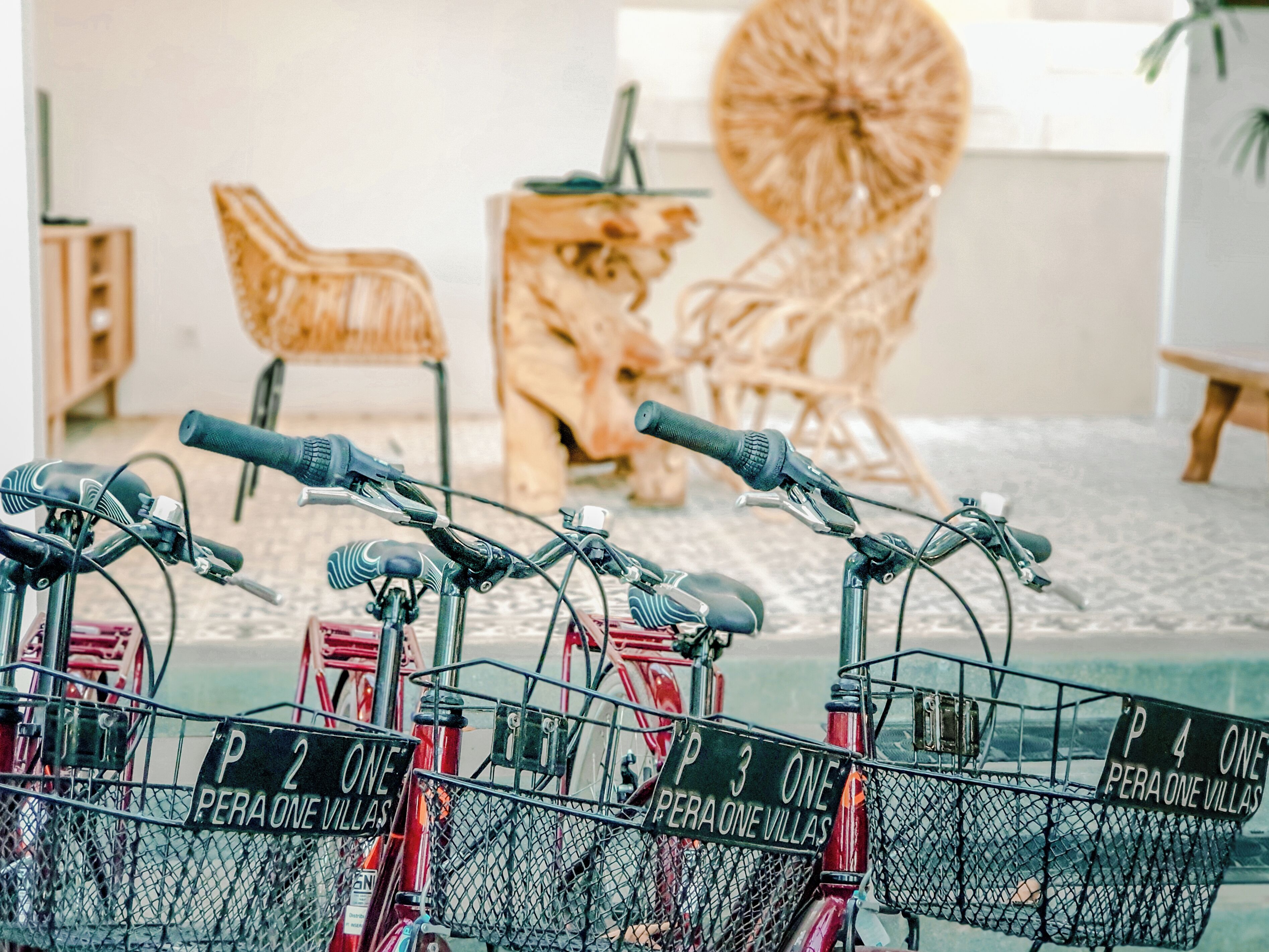 Bicycles with baskets labeled "Pera One Villas" parked indoors.
