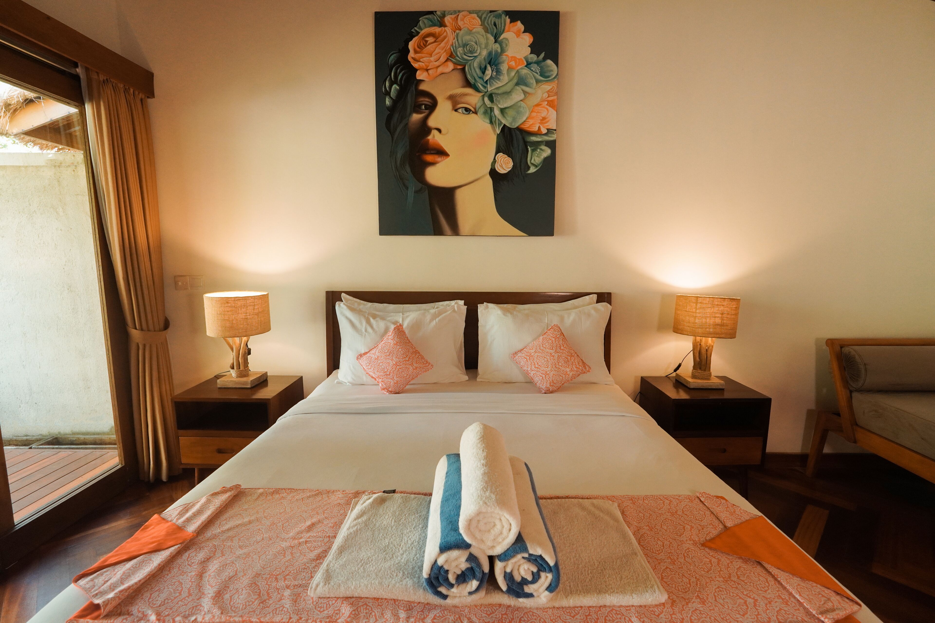 A hotel room with a large bed, two bedside tables with lamps, a painting on the wall, and a window with curtains.