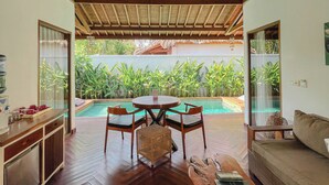 Amplia sala de estar con vista a la piscina, piso de madera y ventilador de techo.