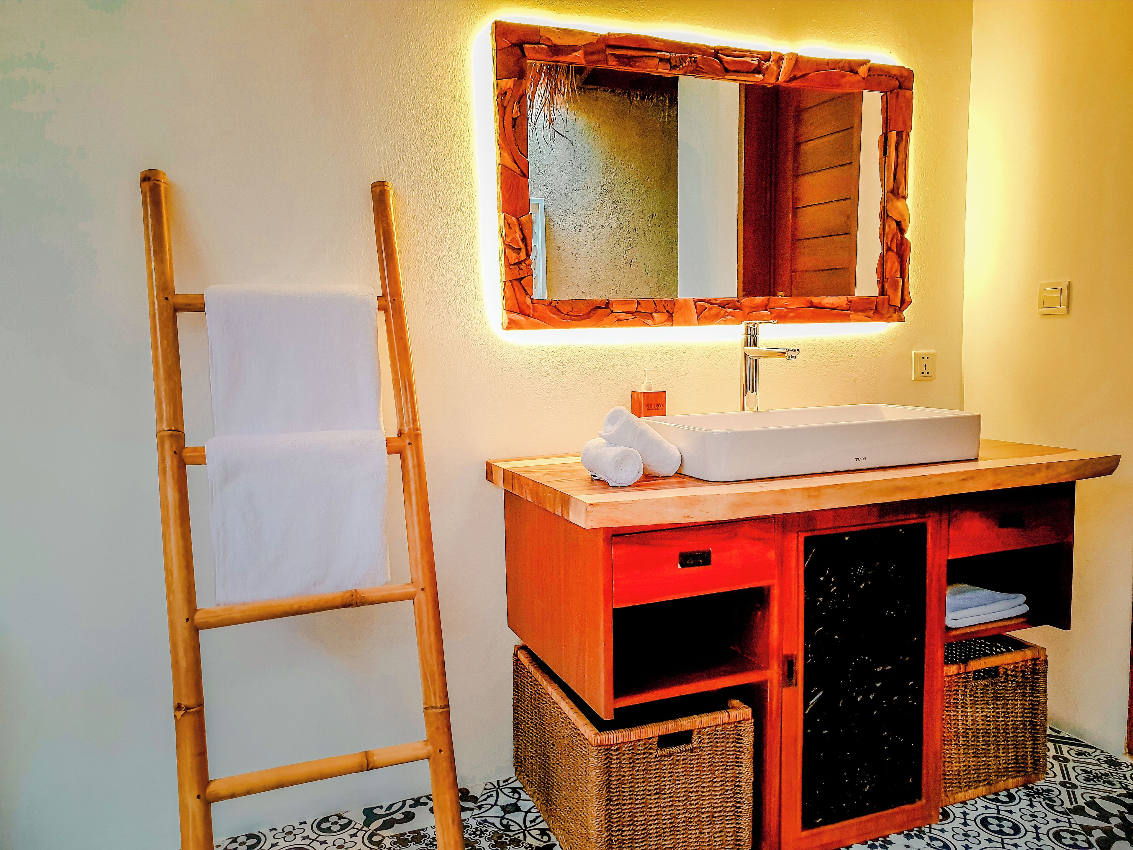 Ein Badezimmer mit einer Holzleiter, einem Waschbecken mit Spiegel und zwei Körben.