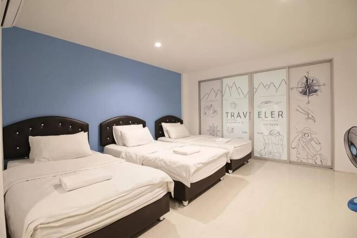 A hotel room with two beds, a large window, and a wall with travel-themed artwork.