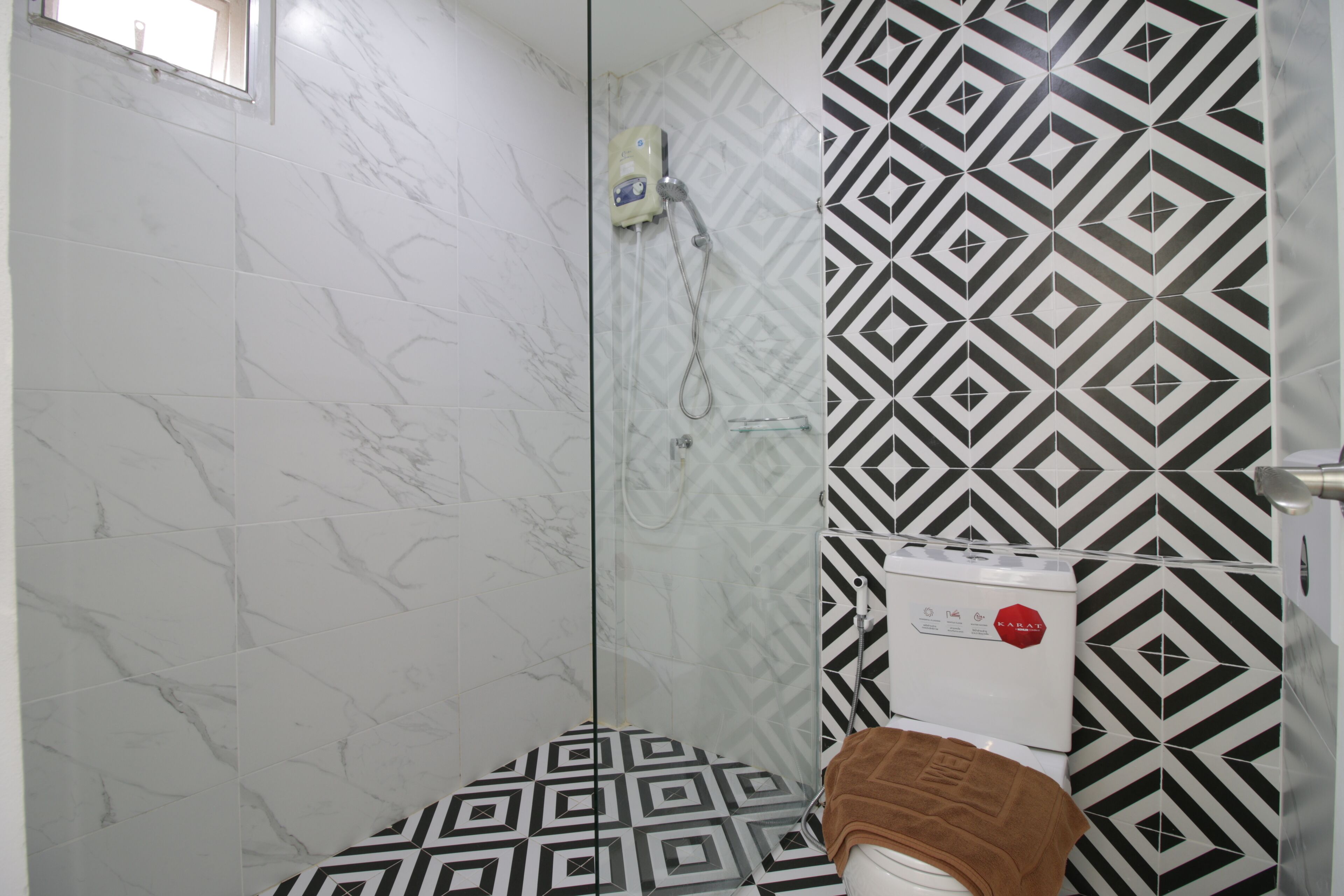 A bathroom with a shower, a toilet, and a patterned wall.