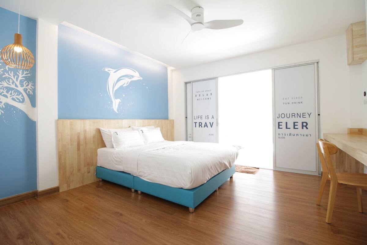 A modern bedroom with a bed, a desk, and a ceiling fan.