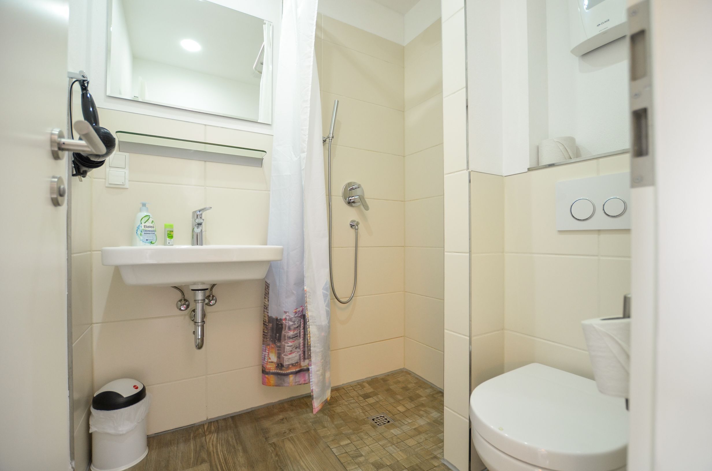 Un baño con lavamanos, inodoro, ducha y espejo.