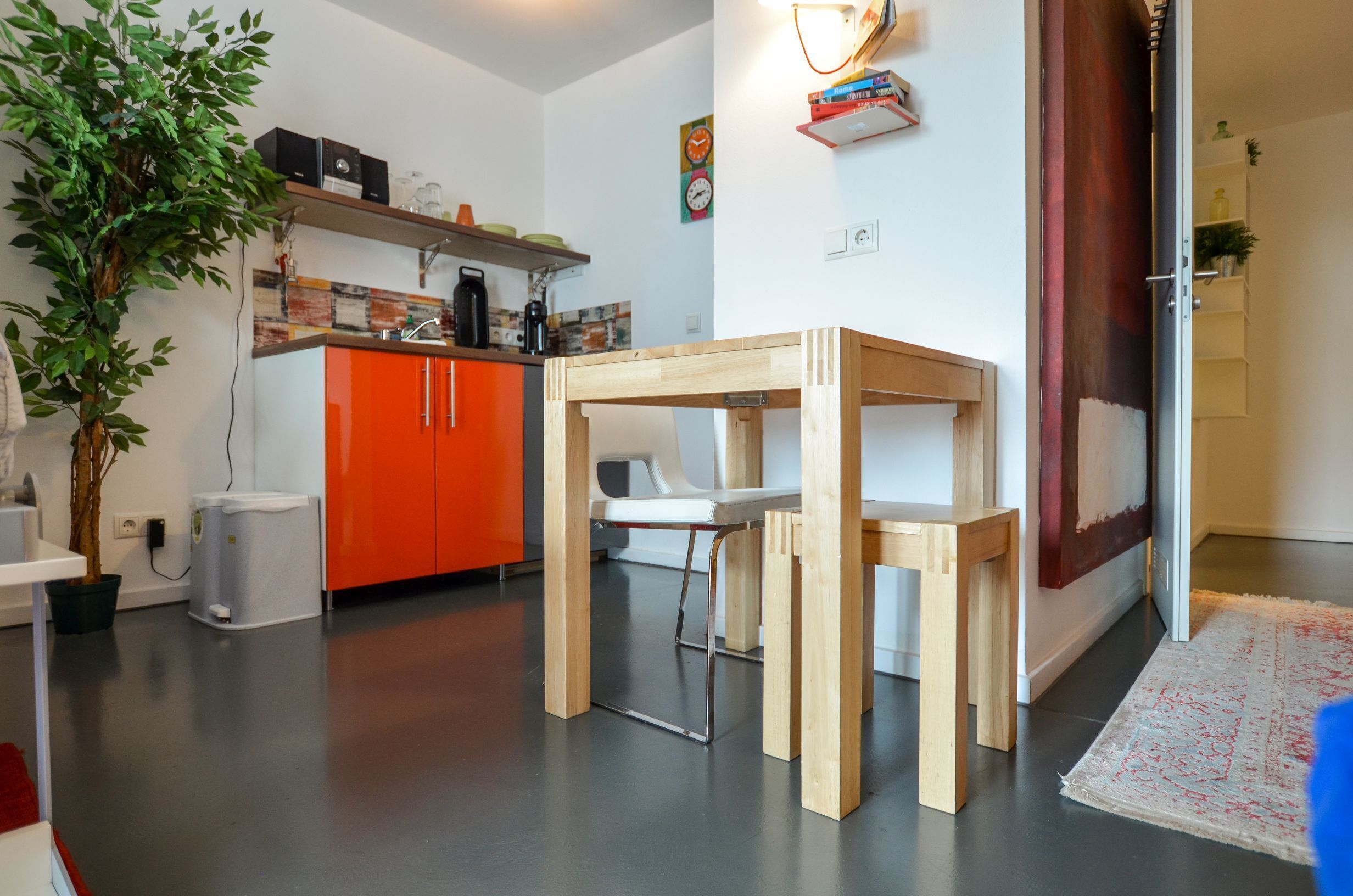 Una cocina moderna con armarios color naranja, una mesa de comedor de madera y una planta en maceta.