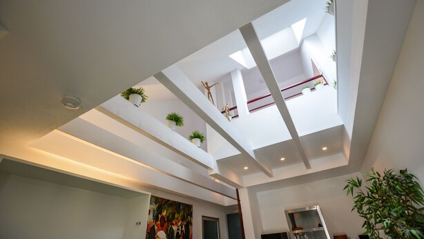 A modern interior with a skylight, white walls, and potted plants. - K314 Bonn Aparthotel - Boardinghouse (Bonn)