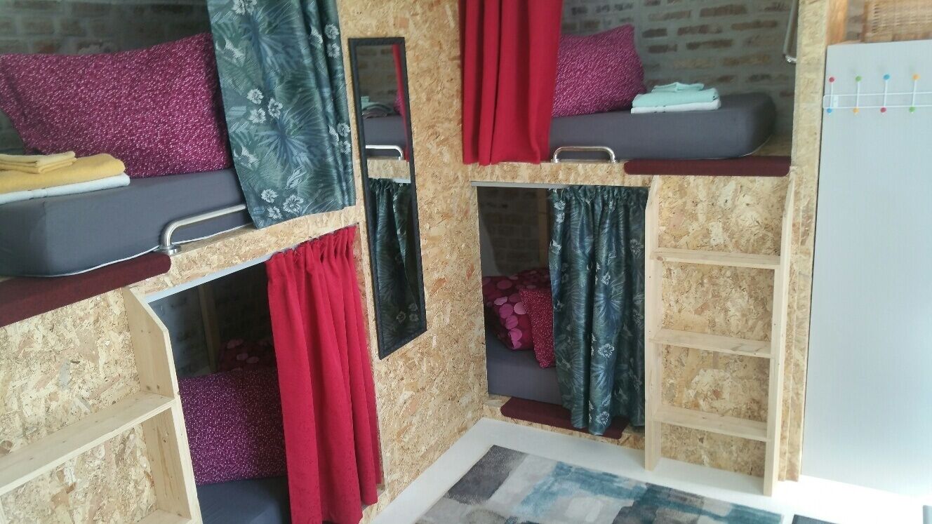 A bunk bed room with a mirror, red curtains, and a small shelf.