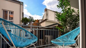 A patio area with two blue wicker chairs and a metal railing. - K314 Bonn Aparthotel - Boardinghouse (Bonn)