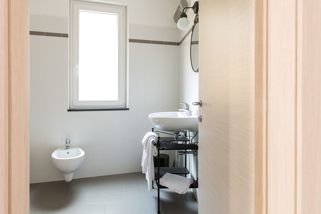 Un baño con bidé, lavamanos y espejo.