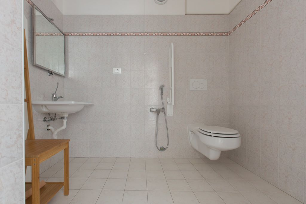 Un baño con lavamanos, espejo, inodoro y ducha.