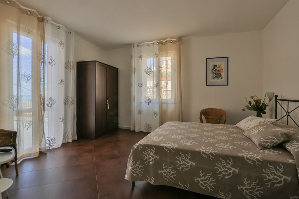 A bedroom with a bed, a wardrobe, a chair, and a window with curtains.