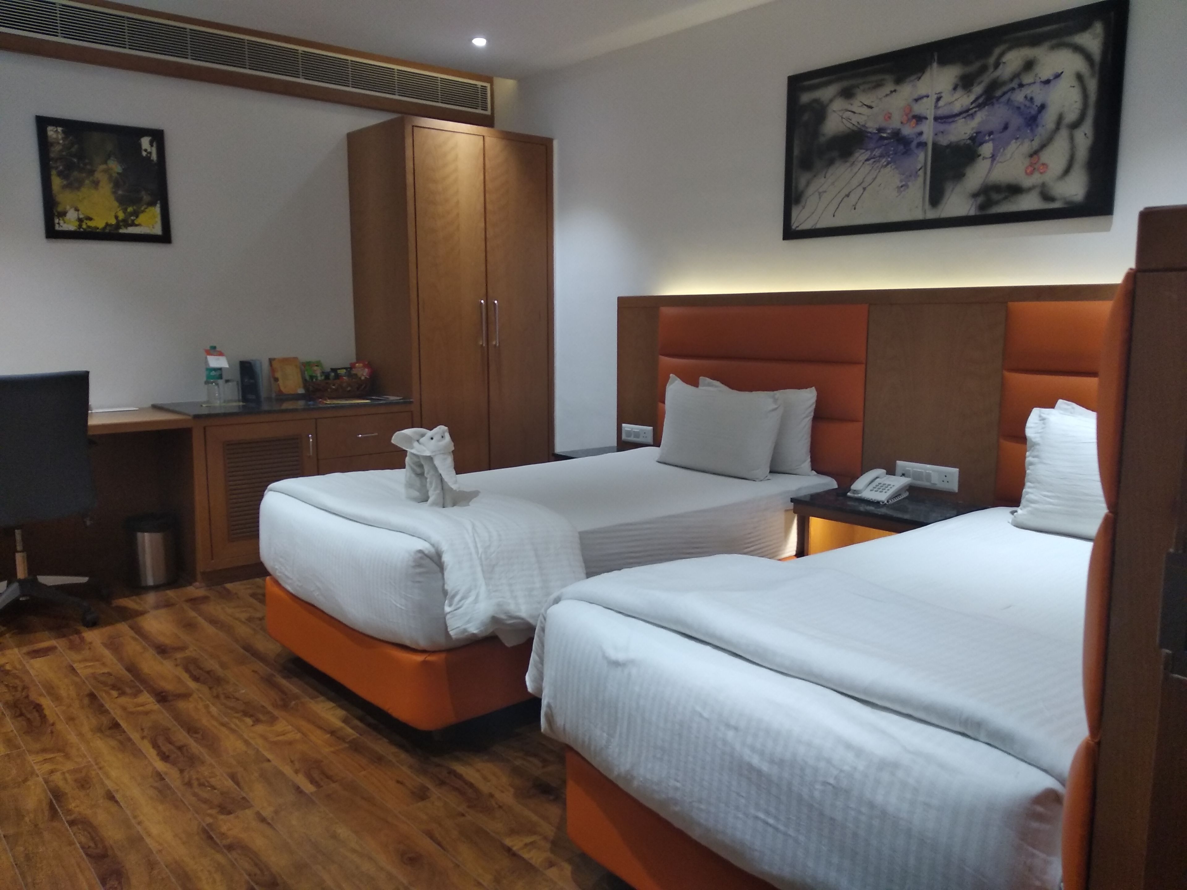 Une chambre d’hôtel avec deux lits, un bureau, une armoire et un tableau au mur.