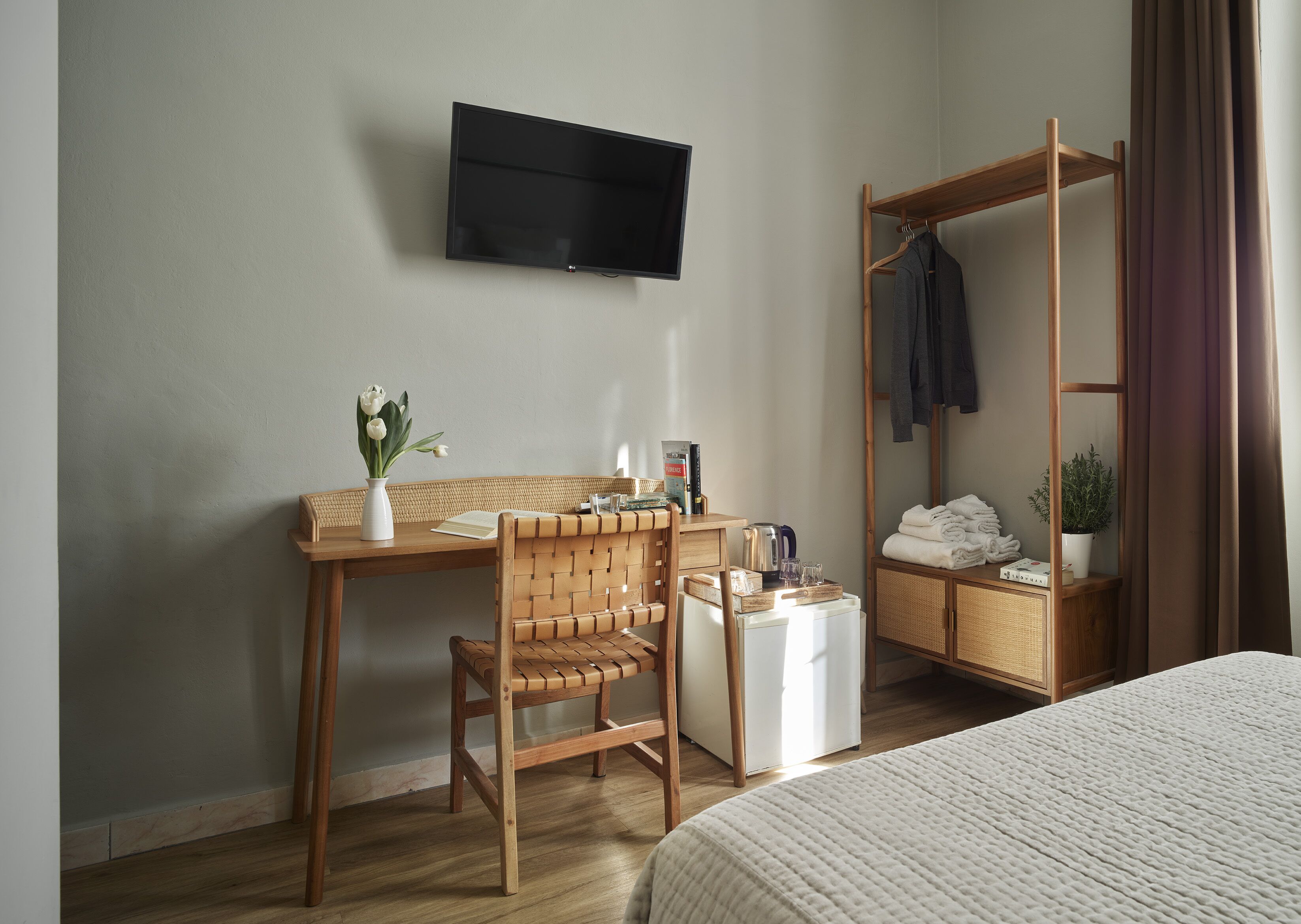 A hotel room with a wooden desk, chair, and a bed with a white textured cover.