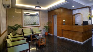 A lobby with a reception desk, seating area, and a mirror. - TreeHouse Neptune Inn (Panaji)