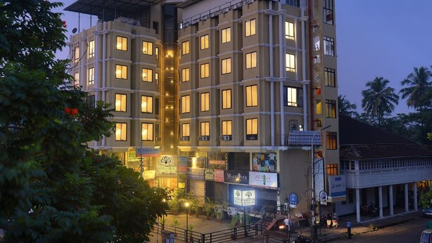 A multi-story hotel with a central atrium, multiple balconies, and a variety of ground-level shops. - TreeHouse Neptune Inn (Panaji)