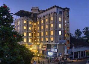 A multi-story hotel with a central atrium, multiple balconies, and a variety of ground-level shops. - TreeHouse Neptune Inn (Panaji)