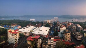 A coastal cityscape with buildings, a river, and a cruise ship in the distance. - TreeHouse Neptune Inn (Panaji)