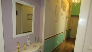 A bathroom with a white vanity, a mirror, a green wall, a wooden floor, and a chandelier. - B&B Speranzella (Naples)
