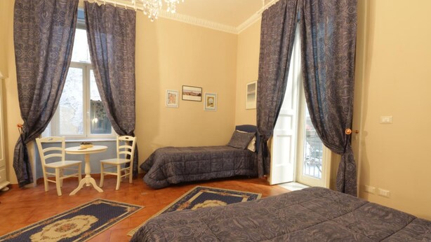 A room with two beds, a small table with chairs, and a window with curtains. - B&B Speranzella (Naples)