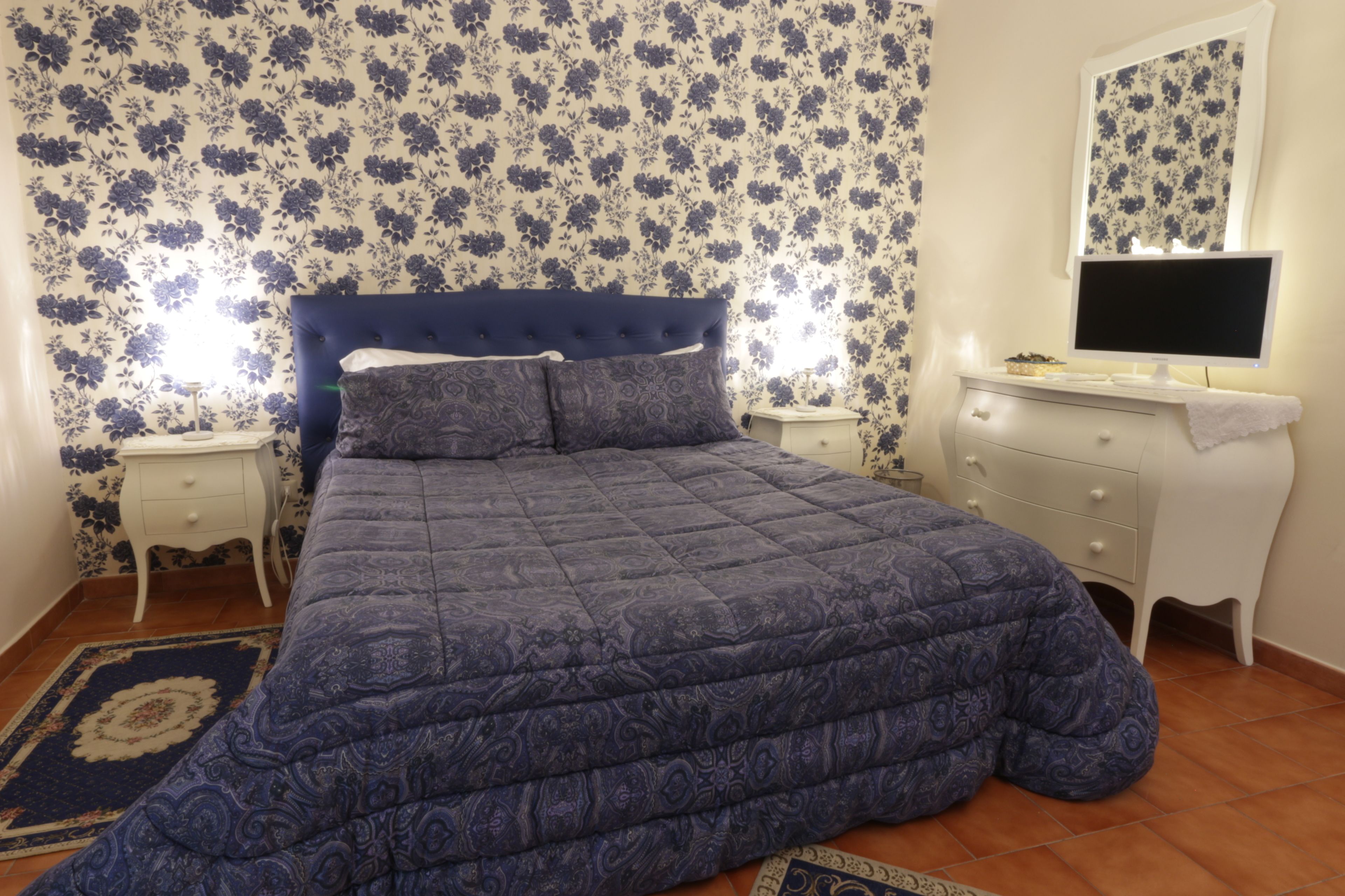 Une chambre à coucher avec un lit, une table de chevet, une commode et un miroir.