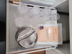 A drawer containing several clear plastic bottles, a metal lid, and a package with Japanese text. - Kawaguchiko Cottage minami (Fujikawaguchiko)