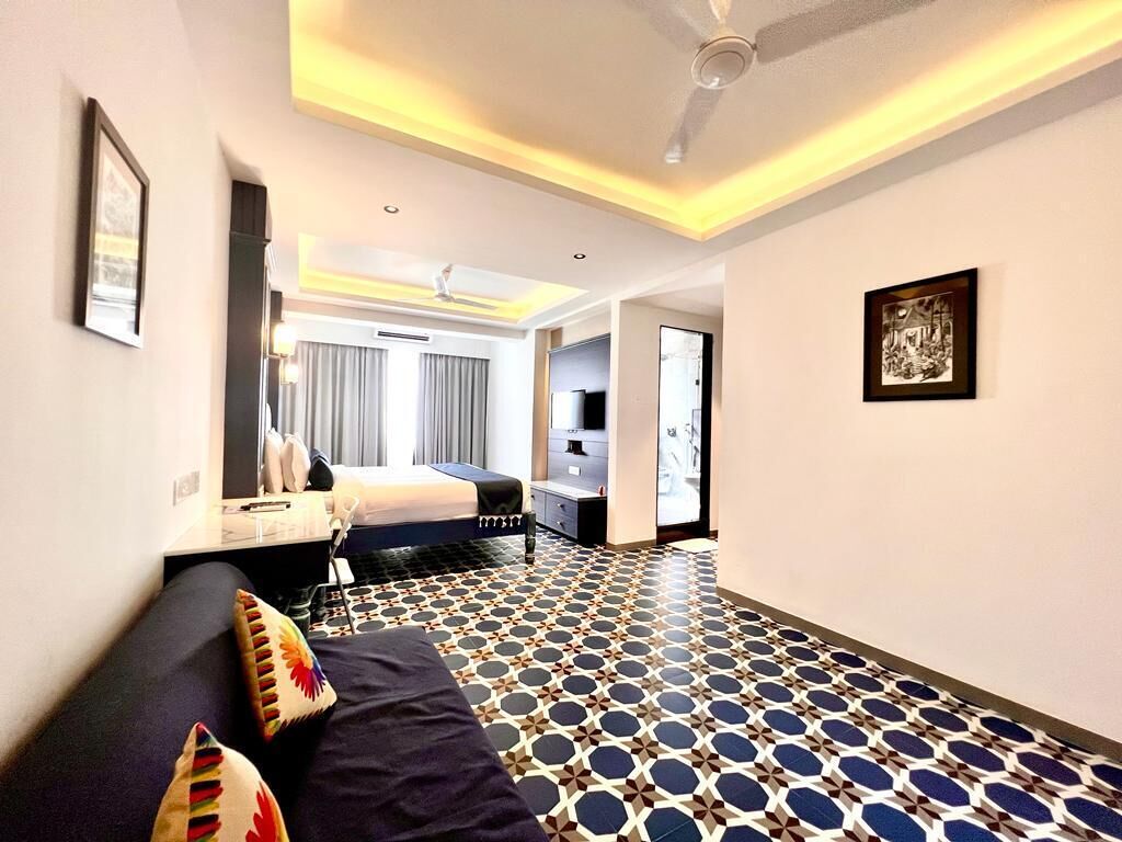 Une chambre d’hôtel avec un lit, un canapé, un ventilateur de plafond et un sol à motifs.
