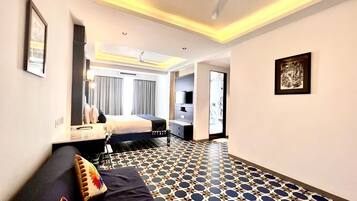 Une chambre d’hôtel avec un lit, un canapé, un ventilateur de plafond et un sol à motifs.