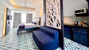 Ein Hotelzimmer mit einem Bett, einer Couch, einer Zierwand, einer Mikrowelle und einer kleinen Küchenzeile.