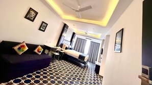 Ein modernes Hotelzimmer mit einem großen Bett, einem Deckenventilator und einem geometrisch gemusterten Boden.